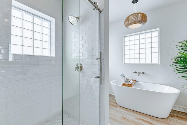 bathroom featuring a wealth of natural light, hardwood / wood-style floors, and shower with separate bathtub