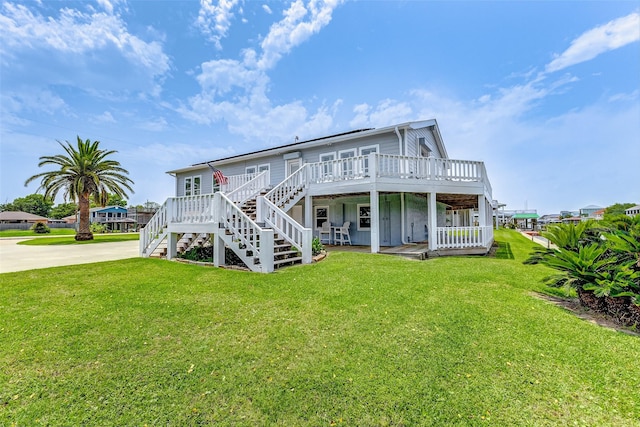 rear view of property with a yard, driveway, a wooden deck, and stairs