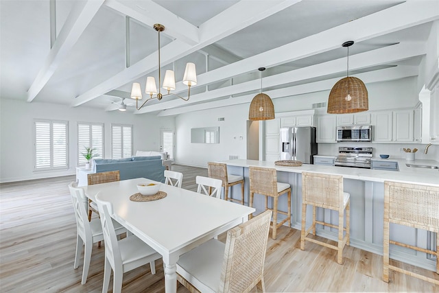 dining space with lofted ceiling with beams, light hardwood / wood-style floors, and sink