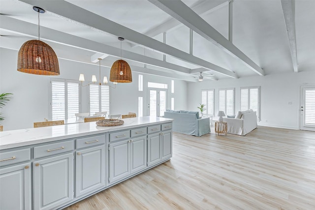 kitchen with light stone counters, ceiling fan, lofted ceiling with beams, gray cabinets, and hanging light fixtures