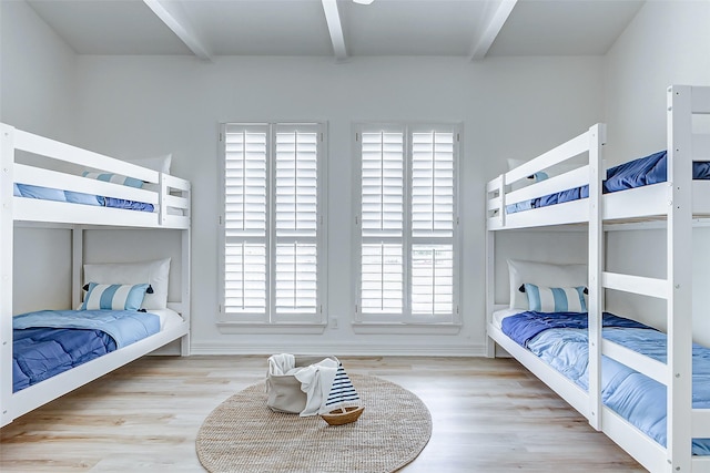 bedroom featuring beam ceiling and light wood-type flooring