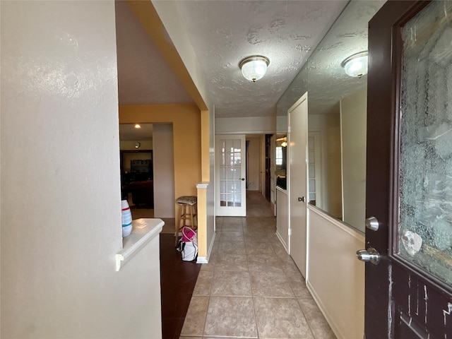 corridor with light tile patterned floors and a textured ceiling