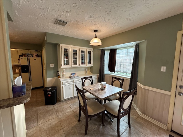 tiled dining room featuring wooden walls and a textured ceiling