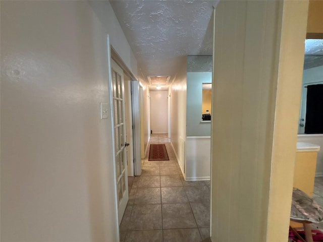 hallway featuring tile patterned flooring and a textured ceiling