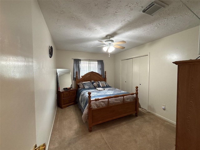 carpeted bedroom featuring ceiling fan, a textured ceiling, and a closet