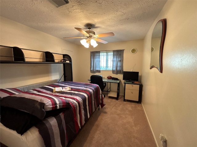 bedroom with a textured ceiling, ceiling fan, and light carpet