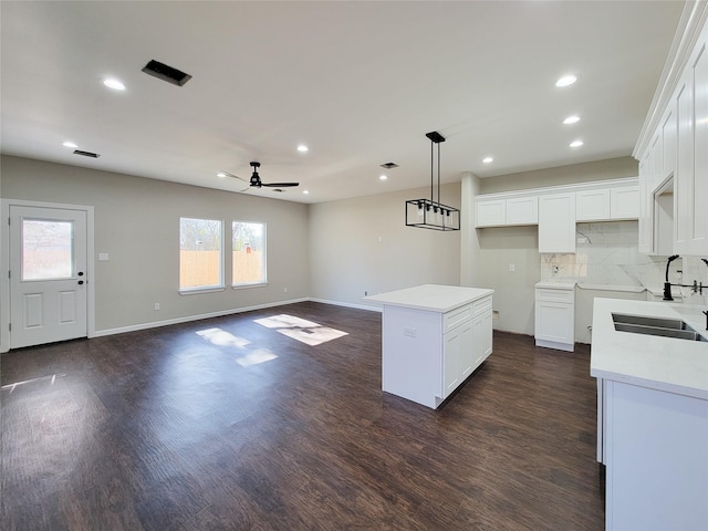 kitchen with a center island, white cabinets, sink, ceiling fan, and decorative backsplash