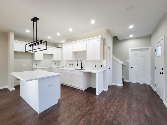 kitchen featuring sink, pendant lighting, white cabinets, washing machine and dryer, and a kitchen island