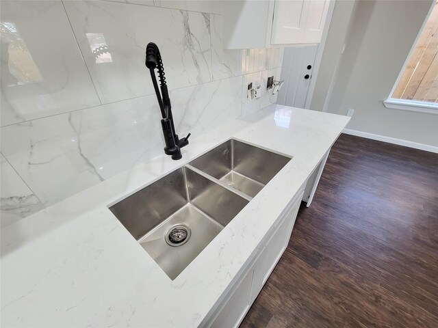 interior details with decorative backsplash, dark hardwood / wood-style flooring, light stone counters, and sink