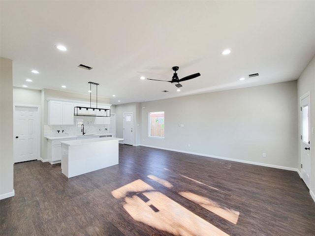 kitchen with tasteful backsplash, a center island, white cabinets, and decorative light fixtures