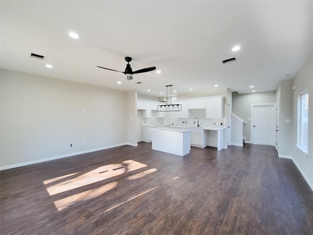 unfurnished living room featuring ceiling fan, dark wood-type flooring, and sink