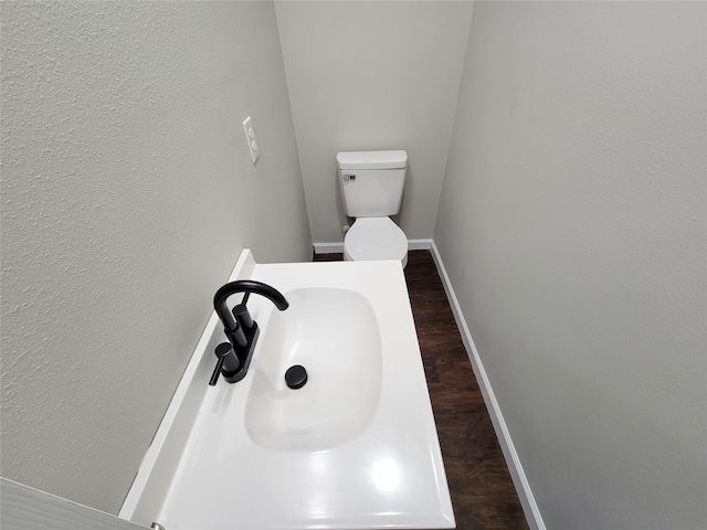 bathroom featuring toilet, wood-type flooring, and sink