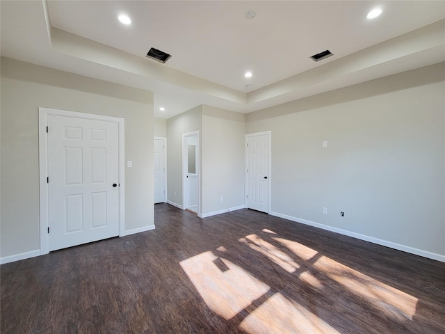 spare room featuring a tray ceiling and dark hardwood / wood-style floors