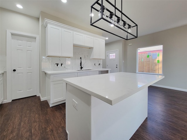 kitchen featuring white cabinets, sink, dark hardwood / wood-style floors, decorative light fixtures, and a kitchen island