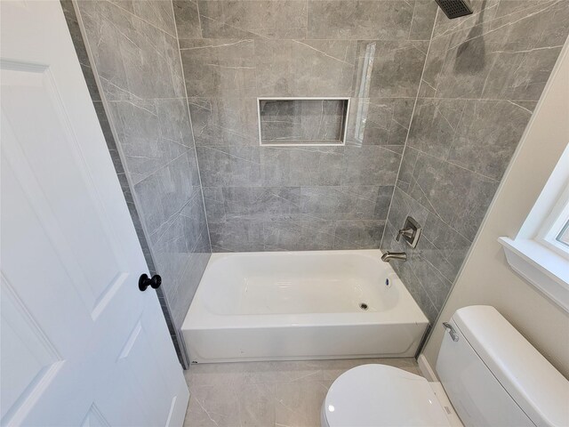 bathroom with tile patterned floors, tiled shower / bath combo, and toilet