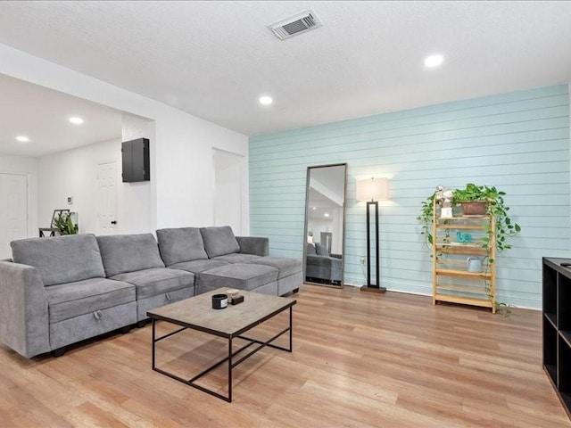 living room with wood walls and light hardwood / wood-style flooring