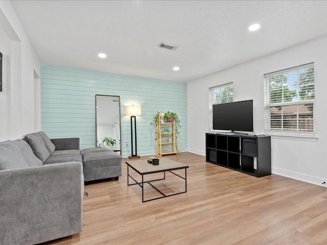 living room with wooden walls and light hardwood / wood-style flooring