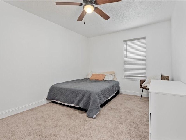 carpeted bedroom featuring ceiling fan and a textured ceiling