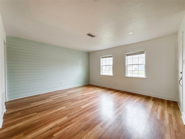 empty room with a textured ceiling and light wood-type flooring