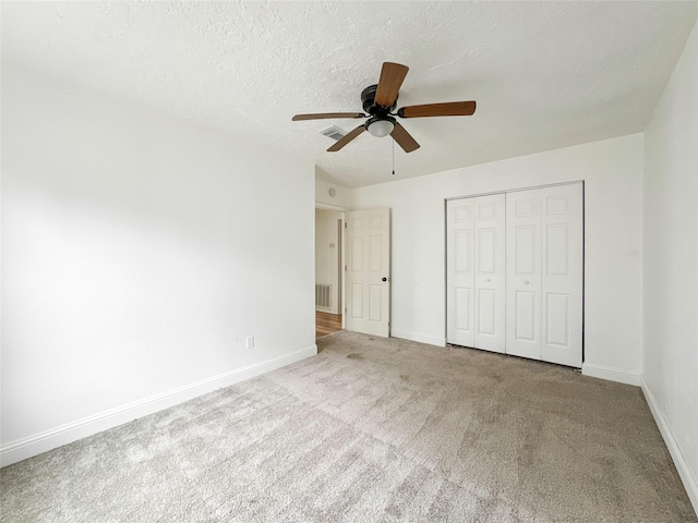 unfurnished bedroom with ceiling fan, a closet, light carpet, and a textured ceiling