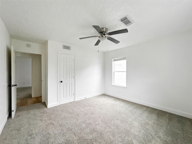 carpeted empty room featuring ceiling fan and a textured ceiling