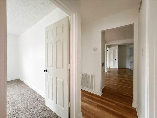 hall with dark hardwood / wood-style flooring and a textured ceiling