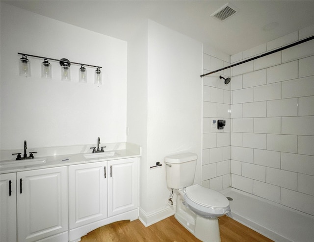 bathroom with vanity, wood-type flooring, a tile shower, and toilet