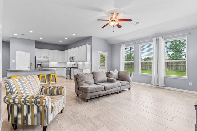 living room with ceiling fan and vaulted ceiling