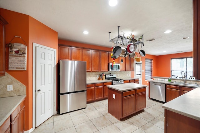 kitchen featuring tasteful backsplash, stainless steel appliances, sink, light tile patterned floors, and a center island