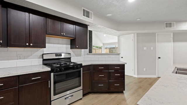 kitchen featuring gas range, a textured ceiling, dark brown cabinets, sink, and light hardwood / wood-style flooring