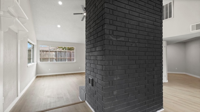 interior space featuring ceiling fan, lofted ceiling, a textured ceiling, and light hardwood / wood-style flooring