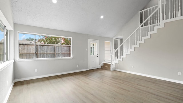 entrance foyer featuring wood-type flooring, a textured ceiling, and vaulted ceiling