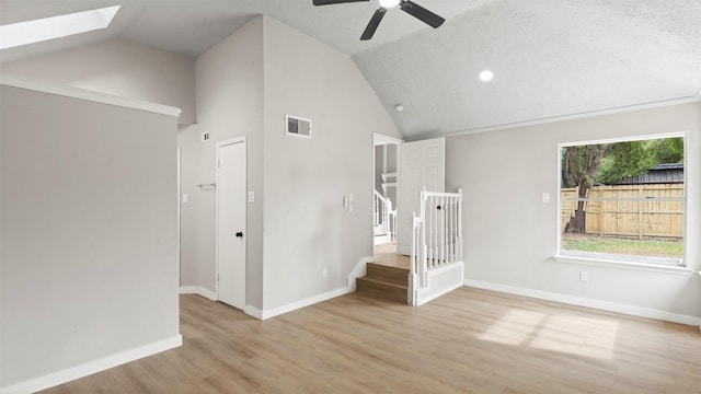 stairs with lofted ceiling with skylight, hardwood / wood-style floors, ceiling fan, and a textured ceiling