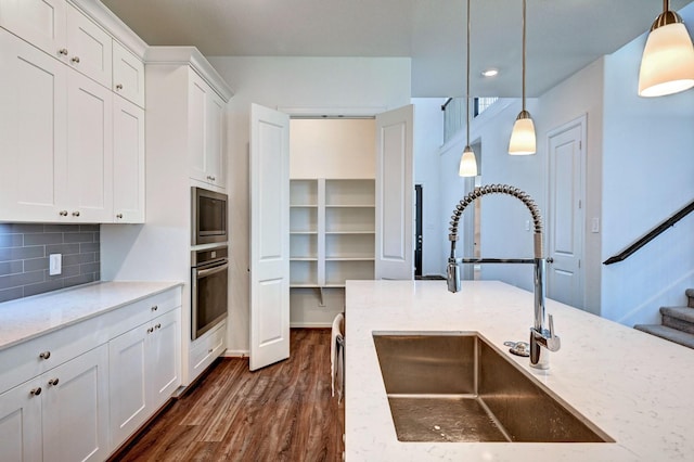 kitchen featuring sink, decorative light fixtures, light stone counters, white cabinetry, and stainless steel appliances