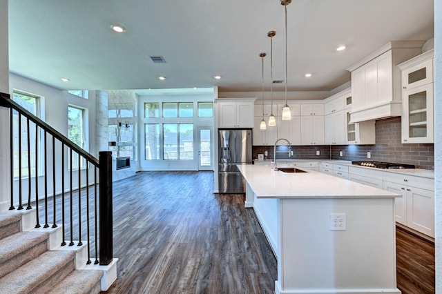 kitchen featuring white cabinetry, sink, stainless steel appliances, an island with sink, and pendant lighting