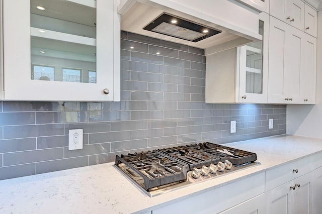 kitchen with tasteful backsplash, white cabinetry, light stone counters, and stainless steel gas cooktop