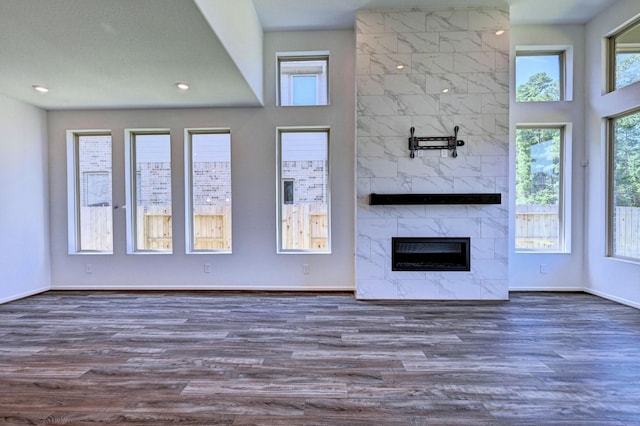 unfurnished living room with a tile fireplace, a wealth of natural light, and dark hardwood / wood-style flooring