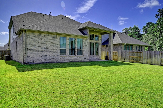 rear view of property with a lawn and central AC