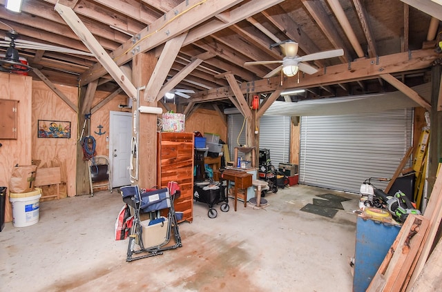 garage featuring ceiling fan and wooden walls