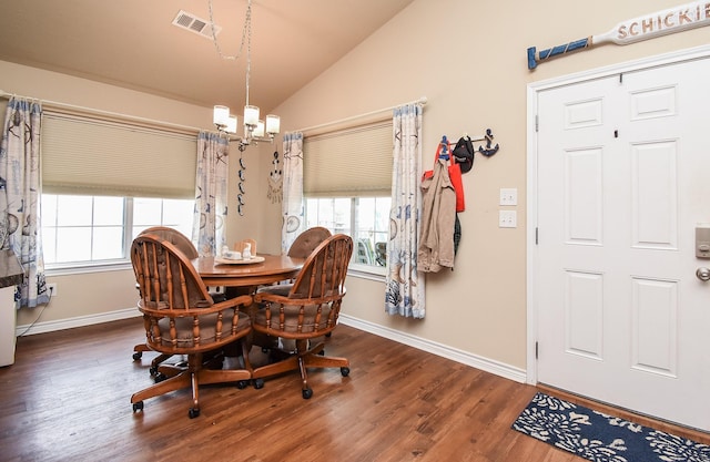 dining room featuring a healthy amount of sunlight, dark hardwood / wood-style flooring, lofted ceiling, and an inviting chandelier