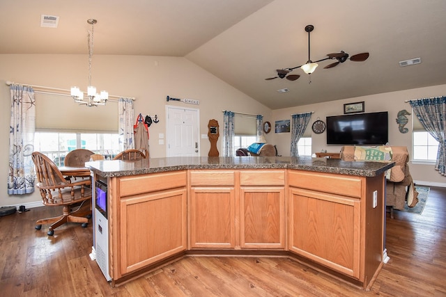 kitchen featuring pendant lighting, light hardwood / wood-style floors, lofted ceiling, a kitchen island, and ceiling fan with notable chandelier