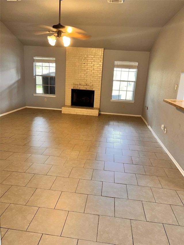 unfurnished living room featuring light tile patterned floors, a brick fireplace, and ceiling fan