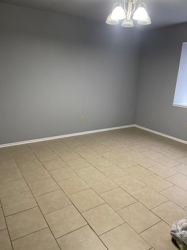 tiled empty room featuring an inviting chandelier