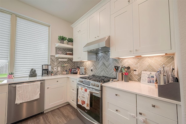 kitchen featuring tasteful backsplash, light stone counters, stainless steel appliances, dark wood-type flooring, and white cabinetry