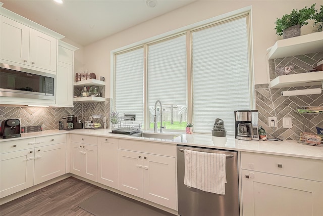 kitchen with decorative backsplash, dark hardwood / wood-style flooring, stainless steel appliances, sink, and white cabinetry