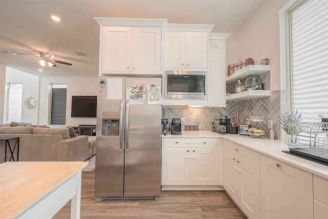 kitchen featuring white cabinetry, built in microwave, stainless steel fridge with ice dispenser, and decorative backsplash