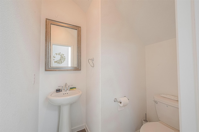 bathroom featuring vaulted ceiling, toilet, and sink