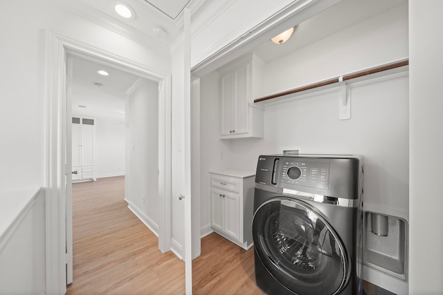 clothes washing area featuring baseboards, washer / clothes dryer, ornamental molding, and light wood finished floors