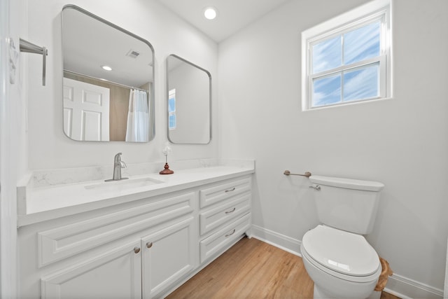 bathroom featuring vanity, wood finished floors, visible vents, baseboards, and toilet