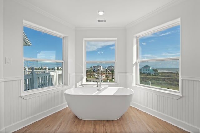 full bathroom with a freestanding tub, visible vents, wood finished floors, wainscoting, and crown molding